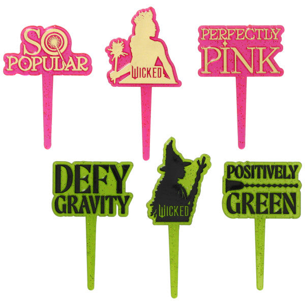 Six Wicked-themed cupcake picks on white background: three in pink (“So Popular,” Glinda silhouette with wand, “Perfectly Pink”) and three in green (“Defy Gravity,” Elphaba silhouette with broom, “Positively Green”), each with glitter accents and pointed stems.