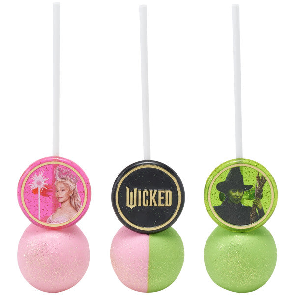 Three cake pops, half pink and half green with shimmer, each finished with a Wicked ring topper: pink princess, black logo, and green witch portrait.