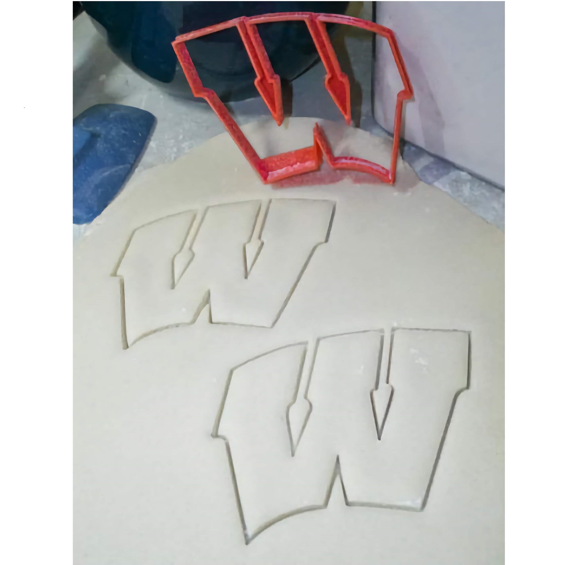 Custom-designed Wisconsin Badgers logo cookie cutter, with red sturdy handle and sharp cutting edges for precise shapes, perfect for sports-themed parties and tailgating. This unique baking accessory is available at Lynn's Cake, Candy, and Chocolate Supplies.