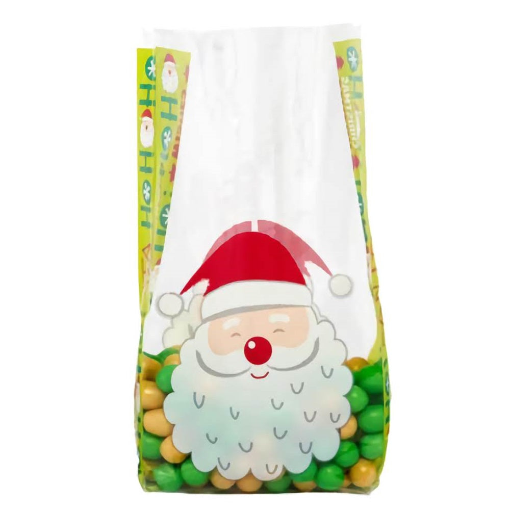 A small-sized 'Wishes For Santa' cellophane treat bag filled with green and gold candies at the bottom. The bag features a cheerful Santa face with a fluffy white beard and red Santa hat. The sides of the bag are adorned with colorful Christmas motifs and the phrase 'Ho Ho Ho,' adding to the festive spirit of the bag. The upper part of the bag is transparent, allowing the colorful candies inside to be part of the overall joyful design.