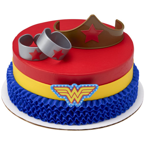 A round cake decorated with the Wonder Woman™ DecoSet®, showcasing a vibrant superhero design with the tiara, arm cuffs, and logo emblem.