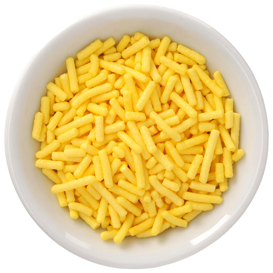 White bowl filled with bright yellow Natural Dyed Made Simply™ rod-shaped sprinkles, shown in a close-up overhead view.