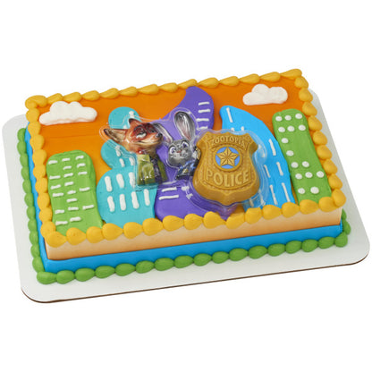 Rectangular sheet cake decorated with colorful city buildings and piped borders, topped with a Zootopia character tray and gold police badge centerpiece.