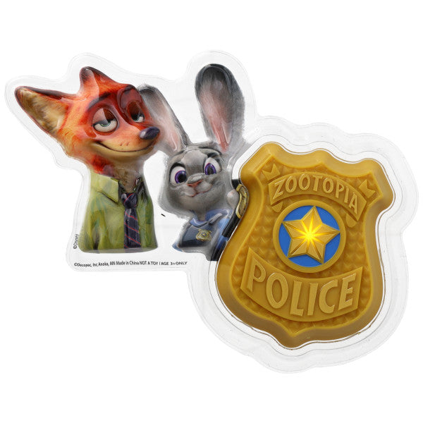 Zootopia cake topper set in a clear plastic tray with an illustrated fox and bunny beside a gold police badge featuring a blue star emblem and “Zootopia Police” text.