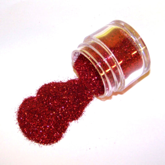 Clear plastic jar tipped on its side spilling ultra-fine sparkling American red glitter dust onto a white background.