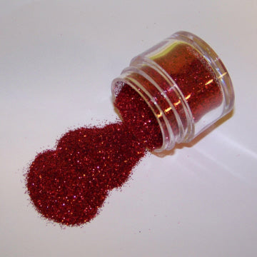 Small jar of red galaxy glitter spilling onto a white surface. Non-edible