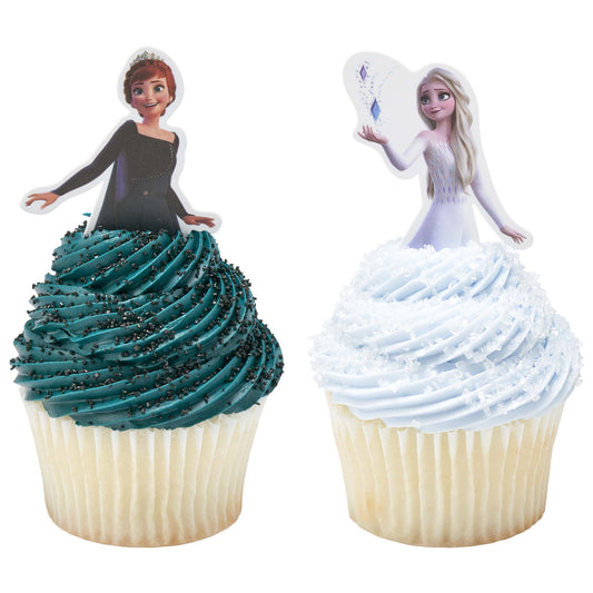 Two cupcakes topped with tall frosting swirls, one with teal frosting & black sanding sugar with an Anna topper pick and one light blue frosting, white sanding sugar and an Elsa topper pick.