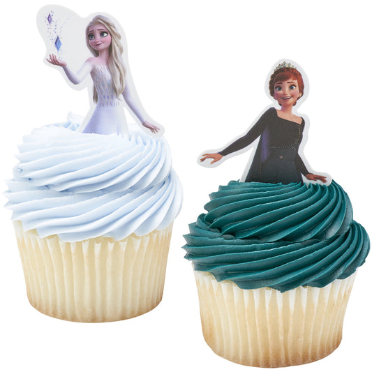 Two cupcakes shown close-up with light blue frosting and an Elsa topper pick, and teal frosting with an Anna topper pick, both in white cupcake liners.