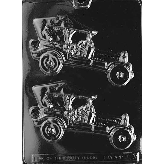 Clear plastic chocolate mold with two large cavities shaped like vintage soft-top antique cars, showing detailed wheels, hood, and cabin features on a dark background.