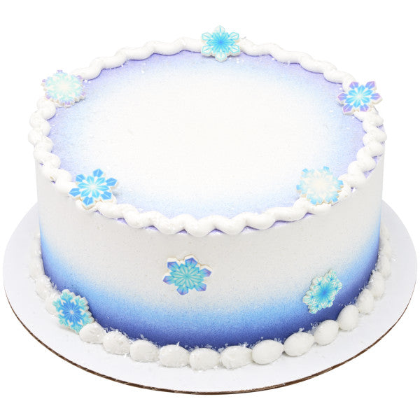 White frosted cake with blue gradient sides, decorated with assorted pressed sugar snowflakes.
