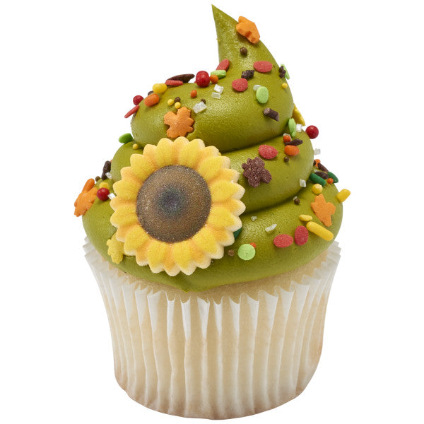 A vanilla cupcake topped with green frosting and autumn sprinkle blend, decorated with a large edible sunflower topper.