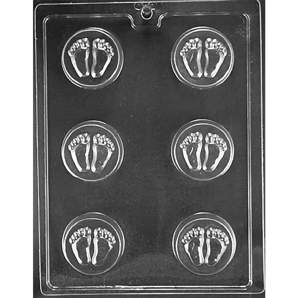 Clear plastic mold with six round cavities, each featuring a raised baby footprints design in the center, shown on a dark background.