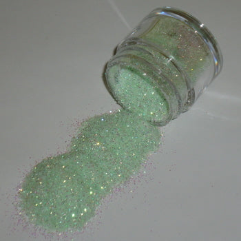 pale baby green Galaxy Glitter Dust spilled from a jar, glowing softly with opalescent shimmer on a neutral surface.
