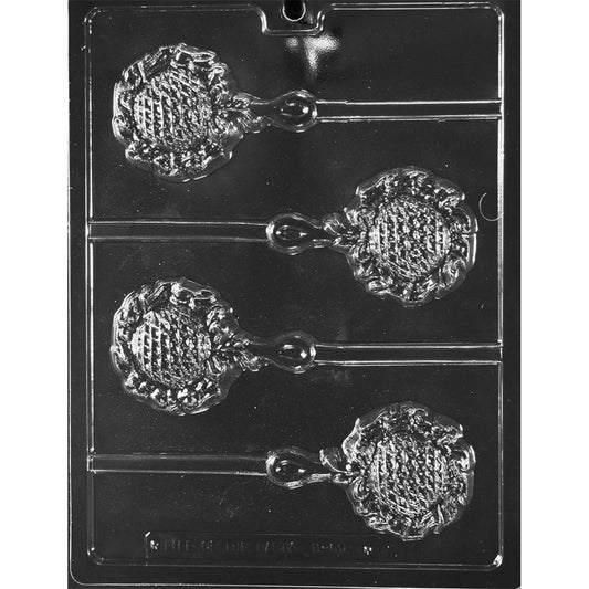 Clear plastic baby rattle chocolate lollipop mold photographed on a black background, showing four rattle-shaped cavities with a textured round head, looped handle detail, and stick channels.