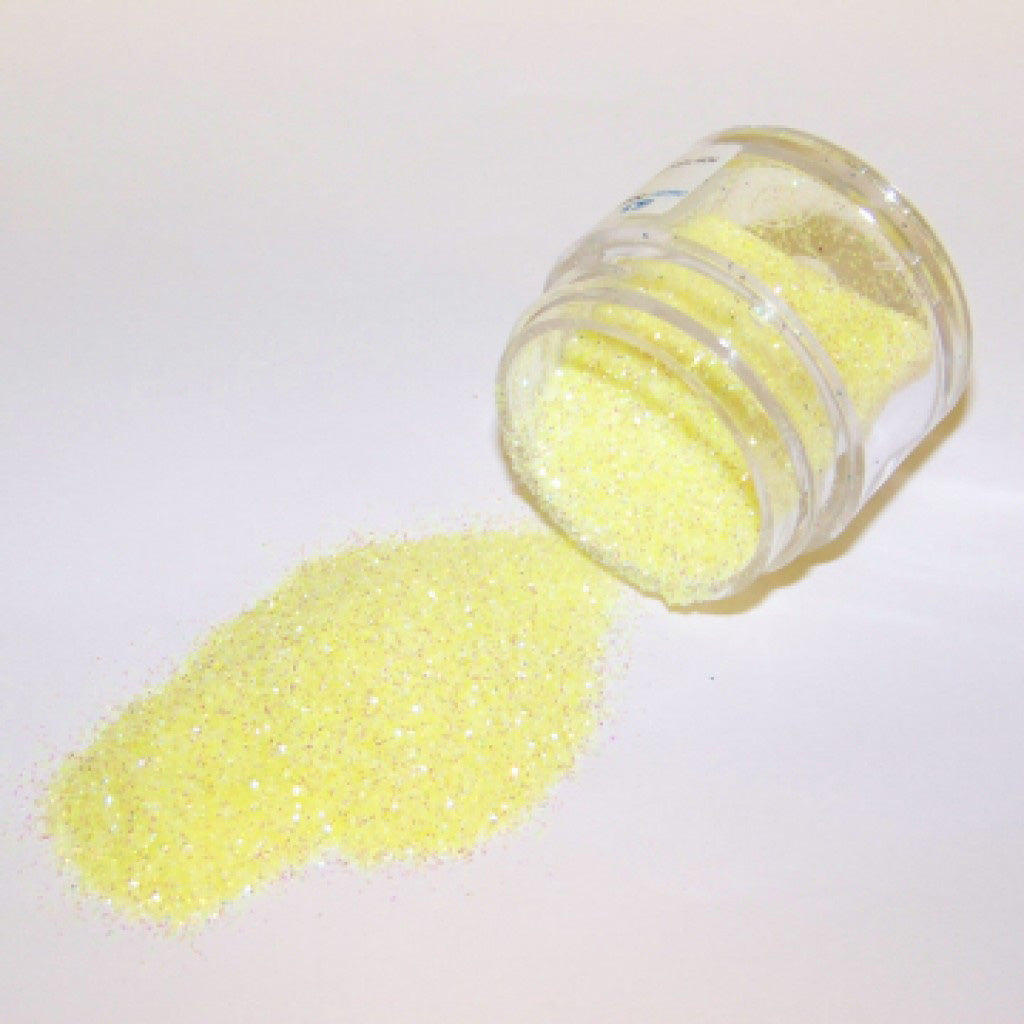 Baby Yellow Galaxy Glitter Dust spilled from a small jar on a white background.