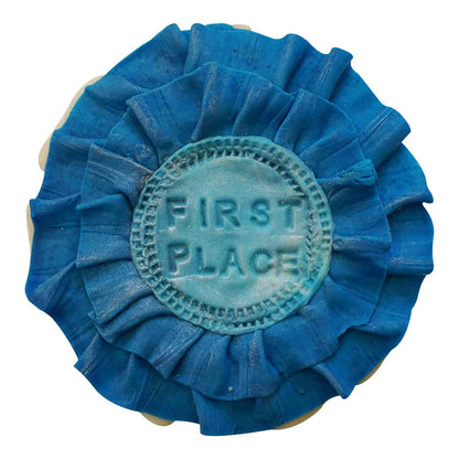 Decorated cookie shaped like a blue first place ribbon with layered fondant and stamped center