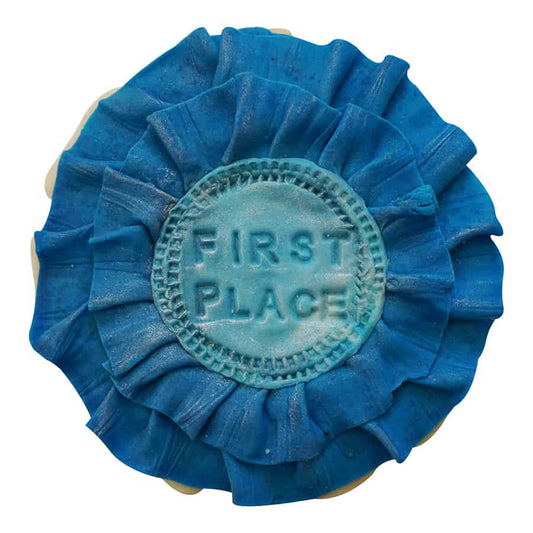 Decorated cookie shaped like a blue first place ribbon with layered fondant and stamped center