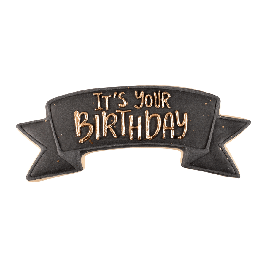 Banner-shaped cookie decorated in black and gold with 'It’s Your Birthday' written in icing.