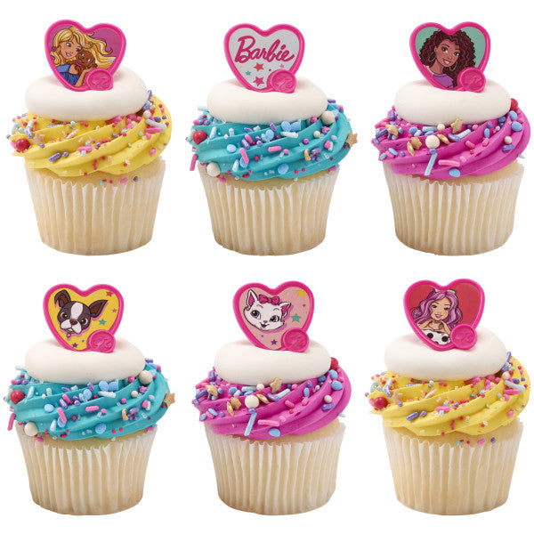 Six frosted cupcakes topped with heart-shaped Barbie cupcake rings in assorted designs, with colorful sprinkles and bright yellow, blue, and pink frosting swirls.
