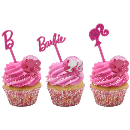 Three cupcakes with pink Barbie-themed picks and glittery Barbie silhouette rings on pink frosting.