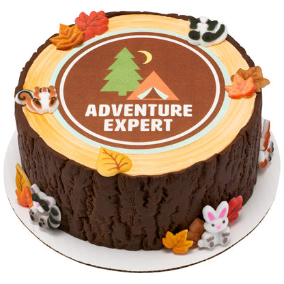 Round cake with printed “Adventure Expert” topper and bark-textured sides