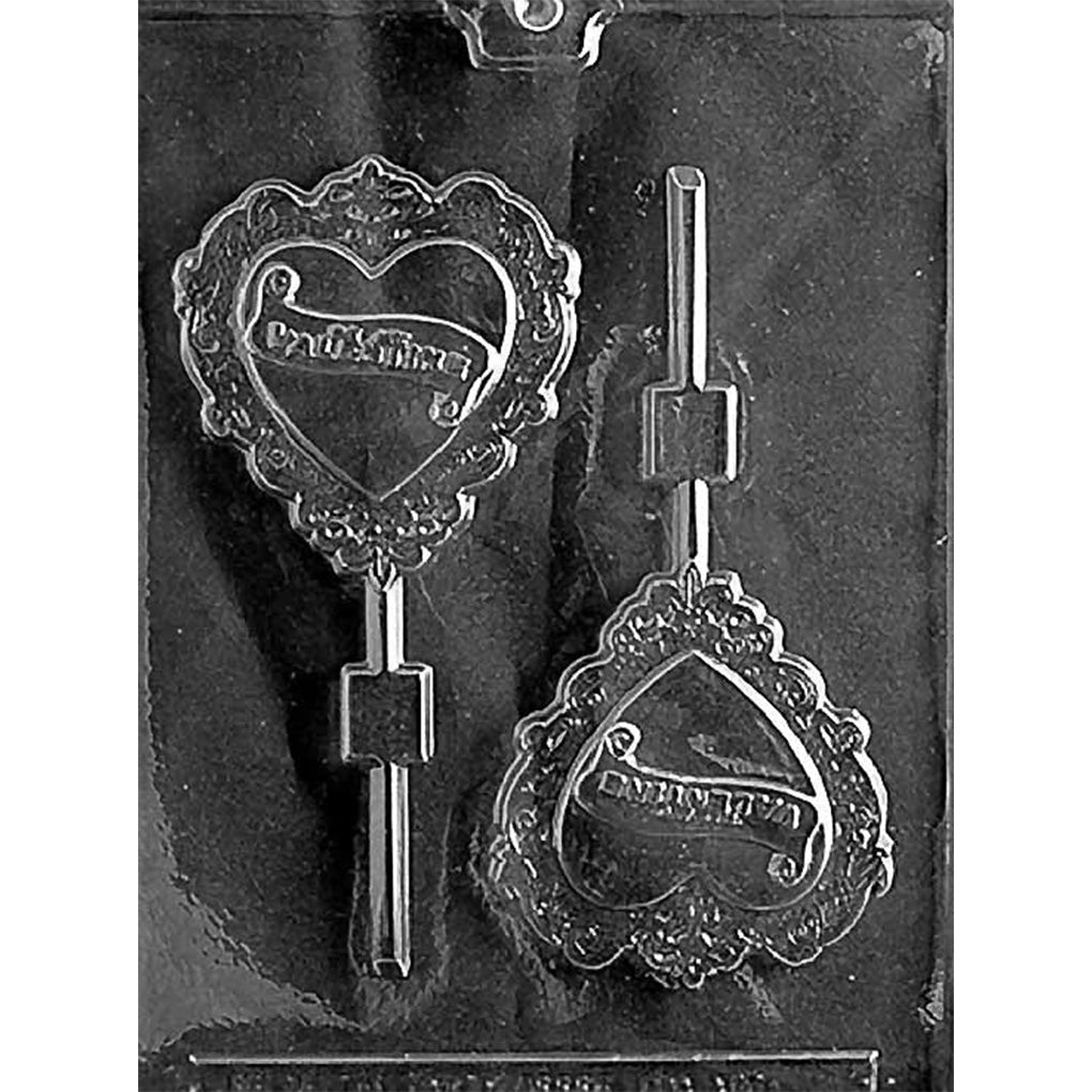 Clear Victorian heart chocolate lollipop mold on dark background, showing ornate lace-edged hearts with embossed “Be My Valentine” banner for romantic candy making.