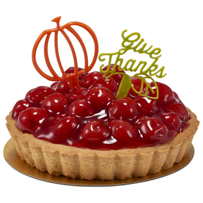 Cherry tart decorated with a green “Give Thanks” topper and an orange pumpkin accent pick.