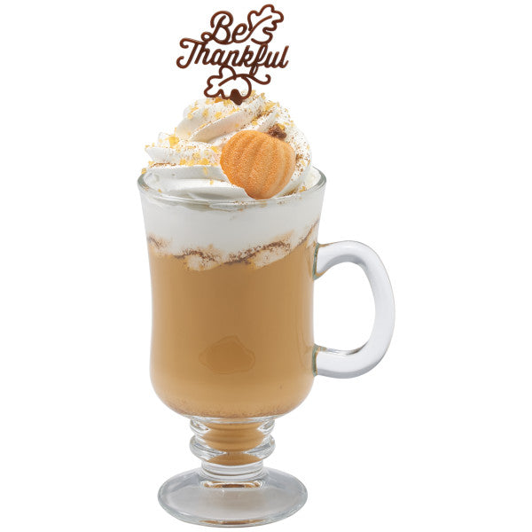 Pumpkin spice latte or dessert drink topped with whipped cream and a brown “Be Thankful” pick.