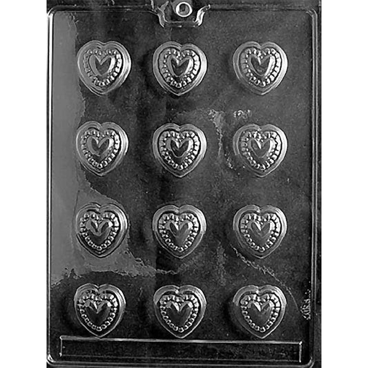 Clear chocolate mold with 12 small heart-shaped cavities, each featuring a raised center heart surrounded by a decorative beaded border on a dark background.