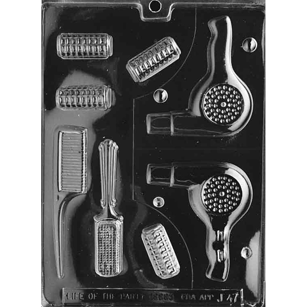 Black plastic chocolate mold with cavities shaped like a 3D hair dryer, comb, brush, hair rollers, and small beautician tools.