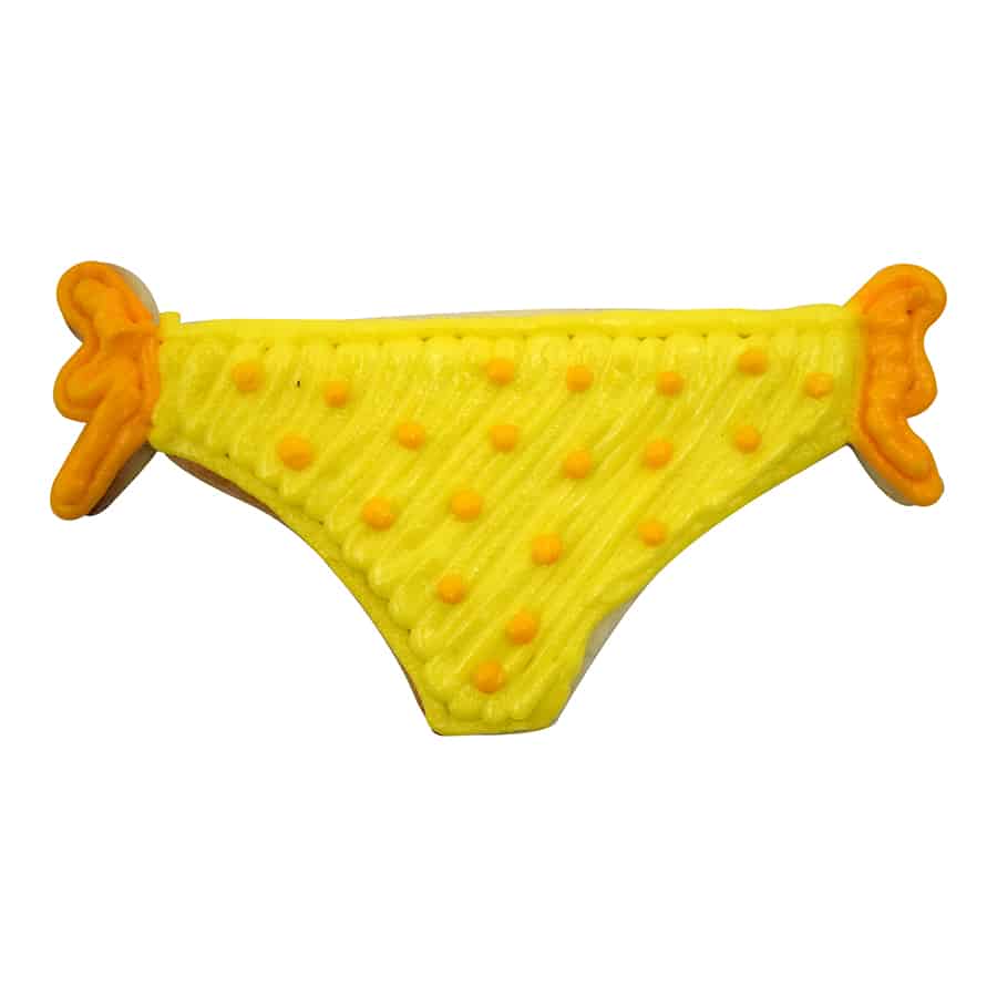 Decorated sugar cookie shaped like bikini bottoms with yellow icing, orange polka dots, and tied ribbon details.