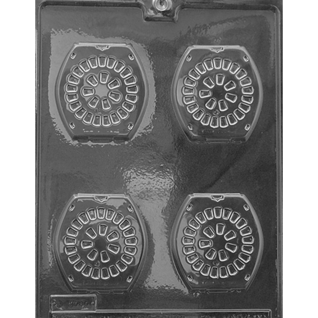 Clear plastic chocolate mold photographed against a dark background with four square-rounded cavities resembling birth control pill packs, each detailed with circular rows of tablet shapes.