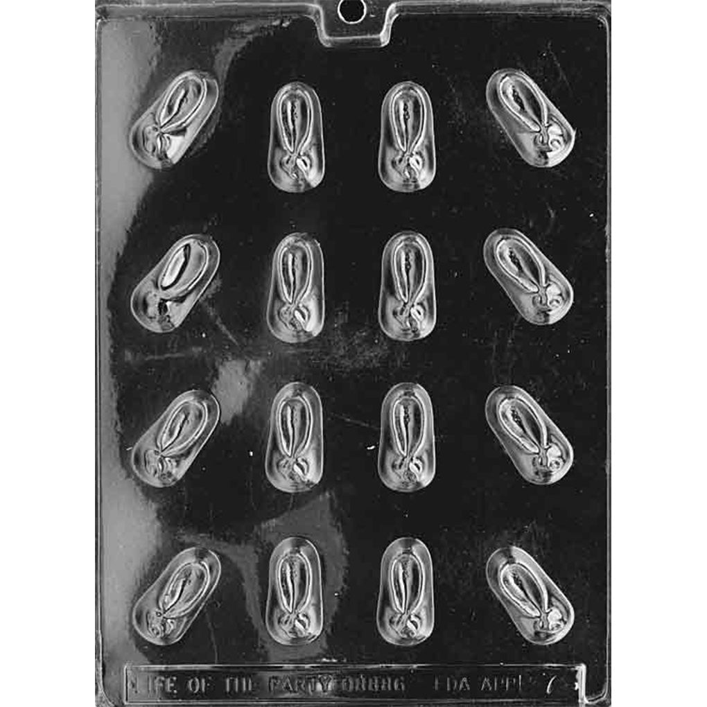 Clear plastic baby booties chocolate mold photographed on a black background, showing multiple small bootie-shaped cavities with raised strap and toe details.