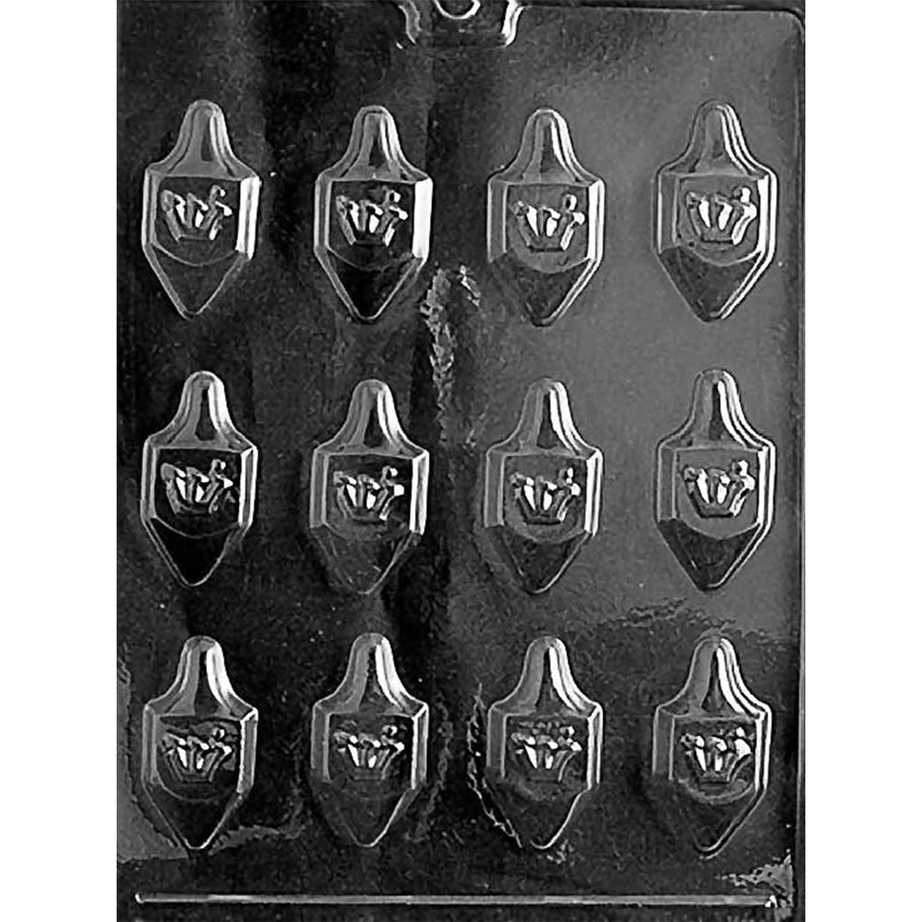 Clear plastic chocolate mold photographed on a black background with multiple bite-sized dreidel-shaped cavities, each showing raised letter details on the front.