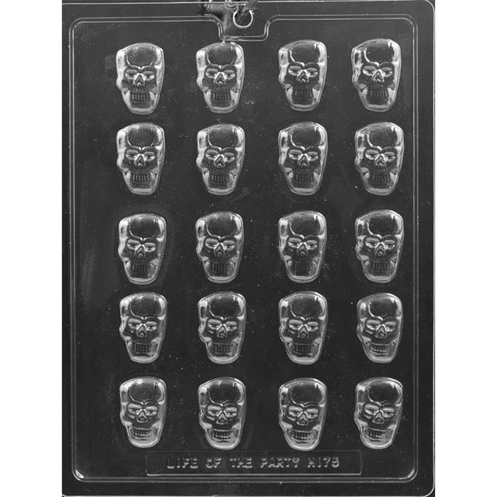 Clear plastic chocolate mold photographed on a dark background with multiple bite-size skull-shaped cavities arranged in rows, each showing eye sockets and a grinning teeth pattern.