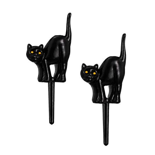 Two black cat cupcake picks with arched backs, raised tails, and orange eyes on a white background.