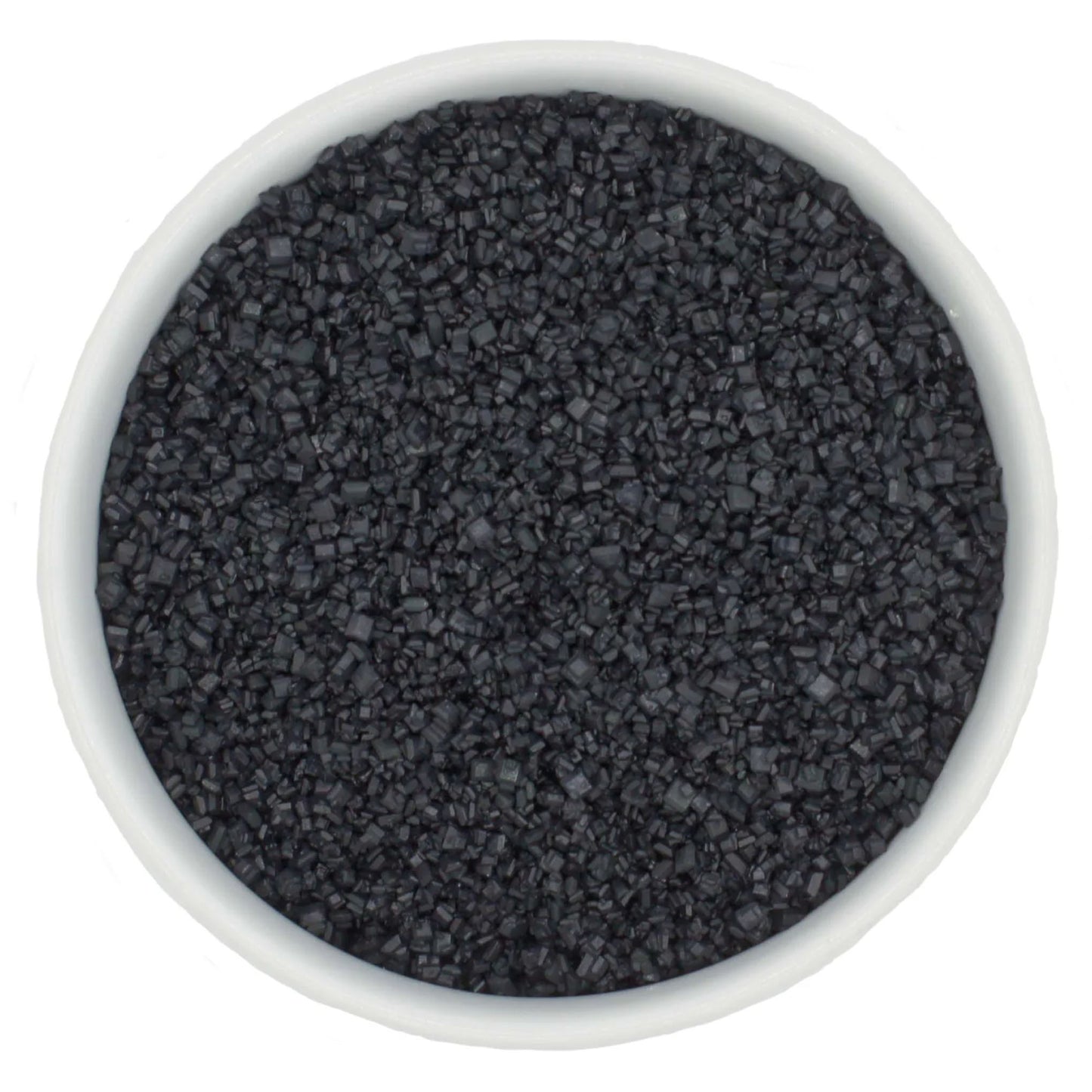 Top-down view of a white bowl filled with black coarse sanding sugar crystals, showing chunky dark granules and a dramatic charcoal-black color.