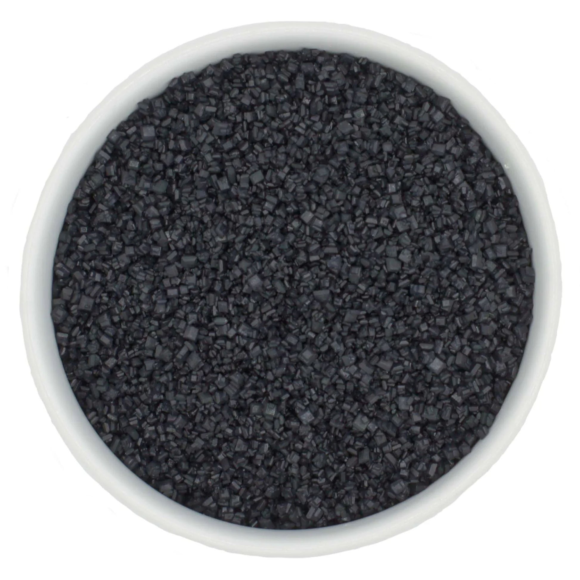 Top-down view of a white bowl filled with black coarse sanding sugar crystals, showing chunky dark granules and a dramatic charcoal-black color.