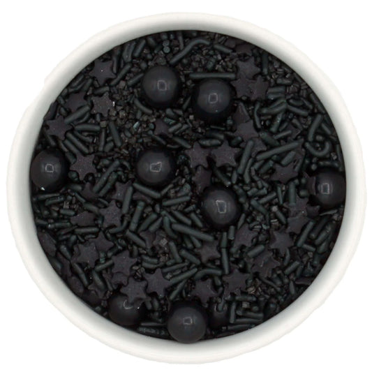 Black Magic all-black sprinkle blend in a white bowl with black jimmies, sugar crystals, star-shaped quins, and round Sixlets