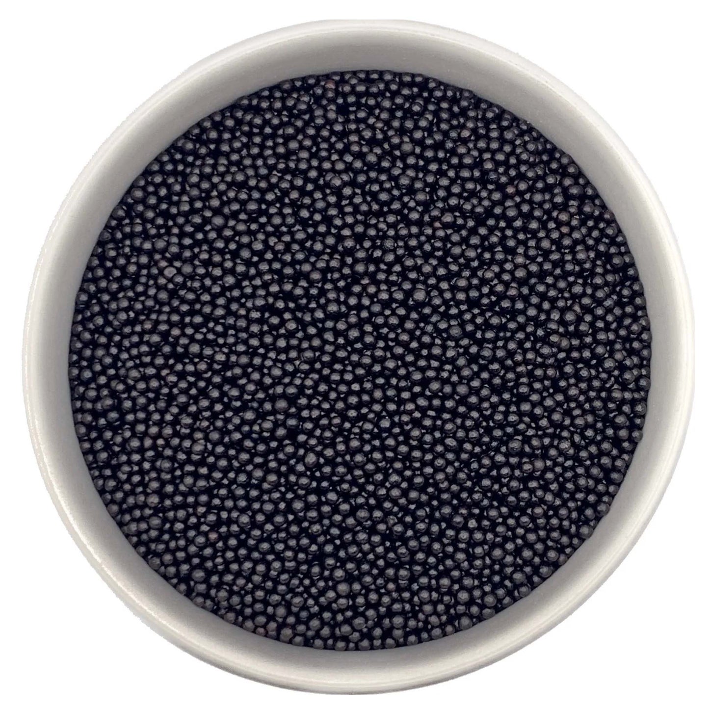 Top-down view of a white bowl filled with black non-pareils, showing tiny round sprinkle beads in a deep charcoal-black shade.