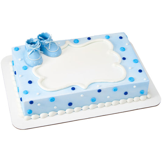 Sheet cake decorated in light blue frosting with white polka dots and topped with blue baby booties cake topper