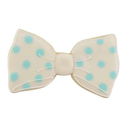 Decorated cookie in the shape of a bow tie, featuring a white base with blue polka dots and delicate icing details