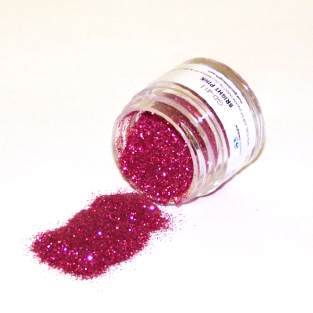 Small clear jar tipped on its side spilling bright pink glitter dust onto a white surface, with fine sparkling particles in a vivid pink shade.
