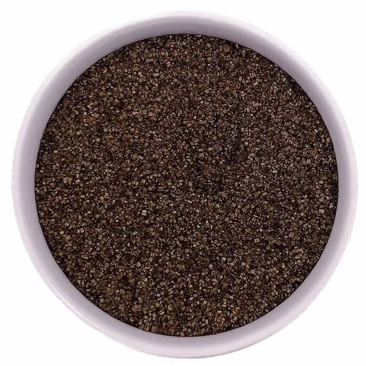 Brown fine sanding sugar crystals in a white bowl on a white background.