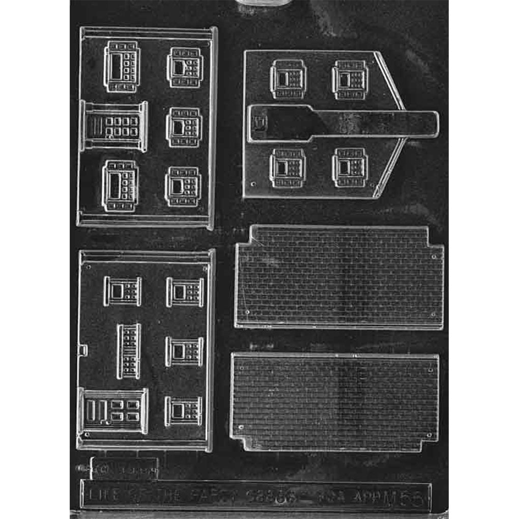 Clear plastic chocolate mold with colonial house building panel cavities, including wall sections with multiple window outlines and roof panels with a shingle pattern for assembling a 3D chocolate house.