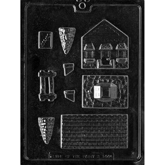 Clear plastic chocolate mold with small house building panel cavities, including a roof piece with shingle texture, wall sections with window outlines, and additional small components for assembling a 3D house.