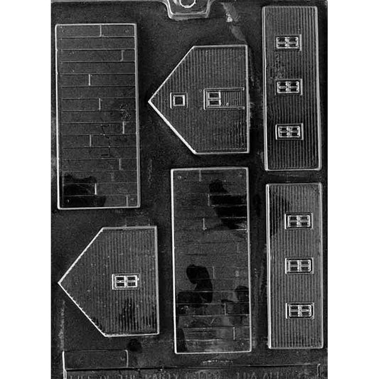 Clear plastic build-your-own schoolhouse chocolate mold showing multiple panel cavities for roof and walls with brick, siding, and window details, arranged on a dark background.