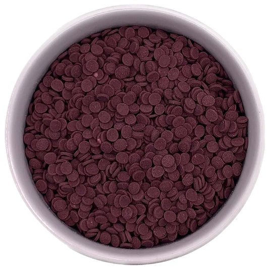 White bowl filled with small flat burgundy confetti sprinkles in a deep wine-red color, shown closely against a white background.