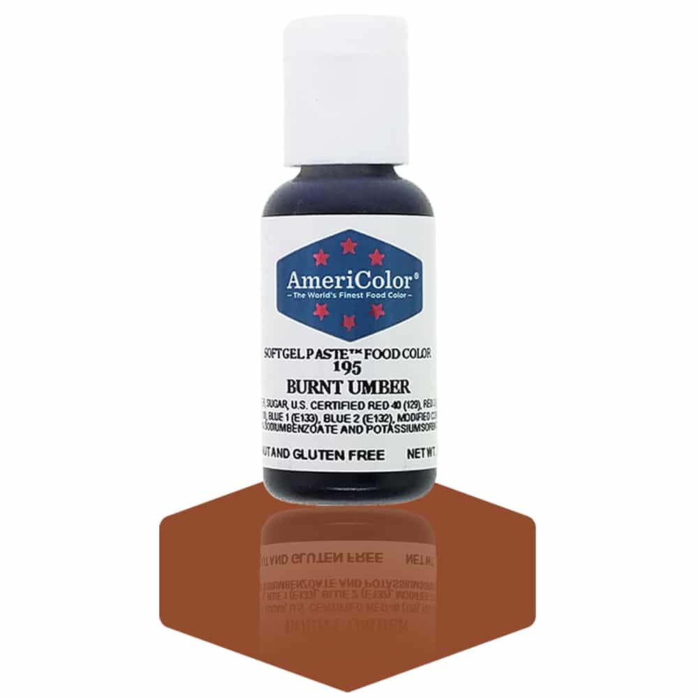 A bottle of AmeriColor Burnt Umber soft gel paste food coloring with a white cap, blue label, and red stars, standing on a rich brown reflective surface that mirrors the bottle.