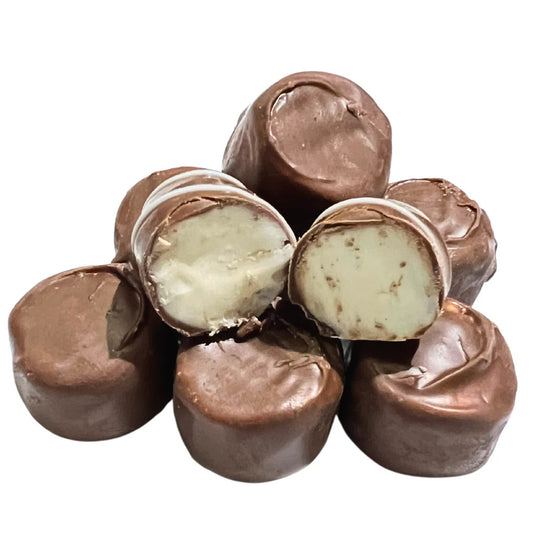 Milk chocolate-covered buttercream candies with one piece cut open to reveal creamy white buttercream filling.